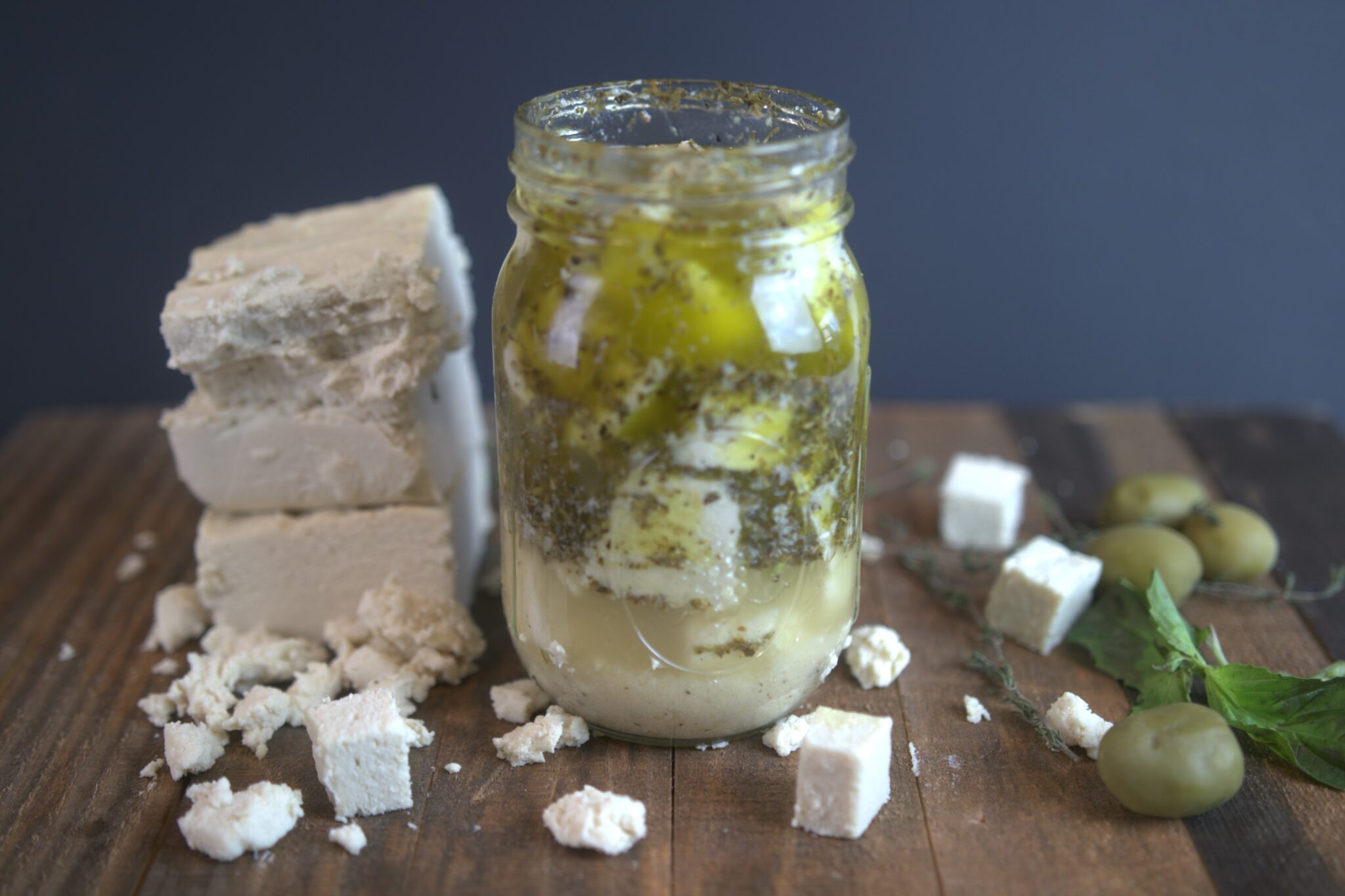 Vegan feta in a jar on a dark wooden board, from TheMushroomDen.com